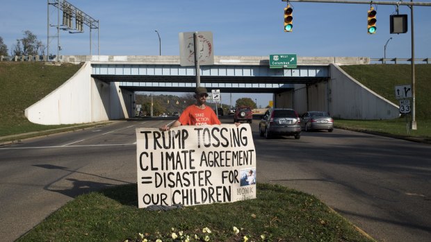 A demonstrator holds a sign protesting against Trump's position on climate change ahead of early voting in Ohio.