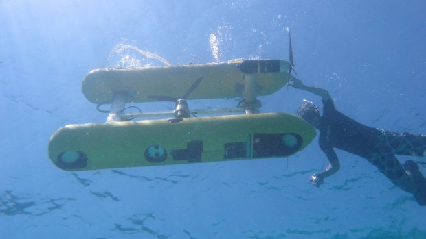 An autonomous underwater vehicle preparing to take high-res images of a coral reef.