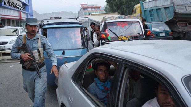 An officer with the Afghan National Police inspects vehicles entering Jalalabad. 