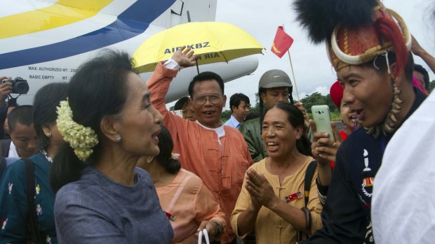 Myanmar opposition leader Aung San Suu Kyi, left, shakes hand with an ethnic Naga man while she is on the  campaign trail in Myanmar's remote Sagaing Division.