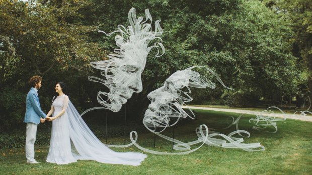 Benjamin Shine and Danielle Stone on their wedding day next to ribbon sculpture "Entwined" by Benjamin Shine.
