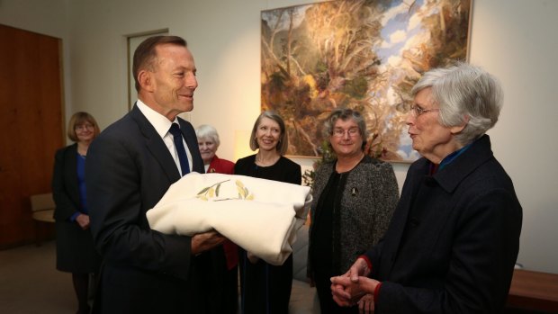 Prime Minister Tony Abbott meets with Audrey Schultz and members of the ACT Embroiderers' Guild to view the baby blanket.