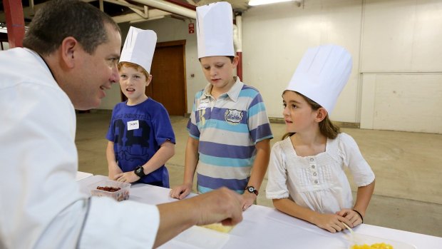 Jayden Newman, 10, Jordan Phillis, 11, and Willow Cosgrove, 9, from Jubilee Christian College get tips from Ekka executive chef Sean Cumming at the Ekka Rural Discovery Day.
