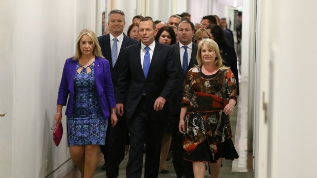 Prime Minister Tony Abbott  arrives for a partyroom meeting on the leadership flanked by supporters.