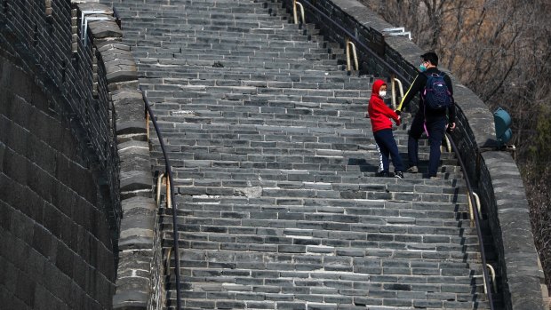 A man and a child wearing protective face masks walk on a stretch of the Badaling Great Wall of China after it reopened following the new coronavirus outbreak in Beijing, China.