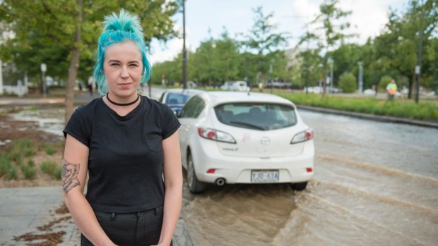 Rhiannon Walker watches as water swamps her car after a water main bursts on Constitution Ave in Canberra.
