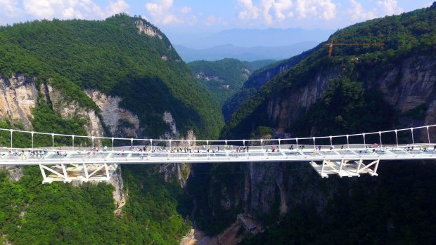 The bridge, which opened to the public on a trial basis on Saturday, spans 430 meters (1,410 feet) and rises about 300 meters (984 feet) above a valley in a scenic zone, making it the world's highest and longest glass-bottomed bridge according to Chinese state media. 