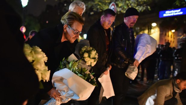 Bono and band members from U2 place flowers on the pavement near the scene of yesterday's Bataclan Theatre terrorist attack in Paris, France.