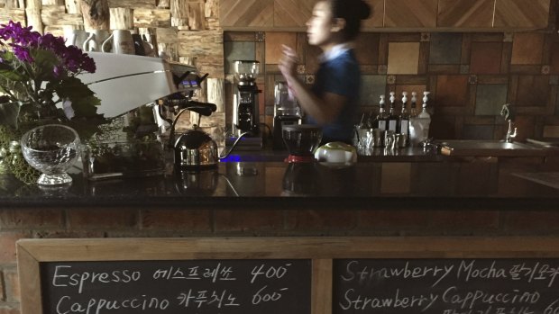 A waitress works behind the counter at the Kumrung cafe where the menu includes the usual favourites of customers in the West.