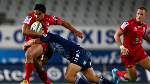 Chris Feauai-Sautia of the Reds is tackled by Jerome Kaino of the Blues.