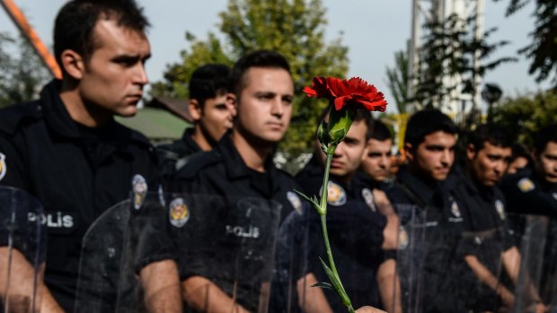 A protester holds a carnation as police block the route to the site of the Ankara explosions. 