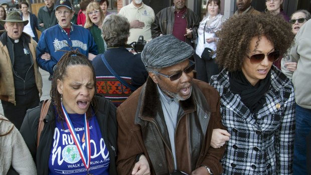Spokane NAACP President Rachel Dolezal, right, link arms and sings 'We Shall Overcome' at a rally in downtown Spokane, Washington, in March after Dolezal received a racist and threatening package.