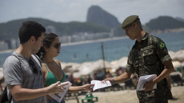 An army soldier distributes a pamphlet about the Aedes aegypti mosquito that spreads the Zika virus on the edge of the Copacabana beach in Rio de Janeiro on Saturday.