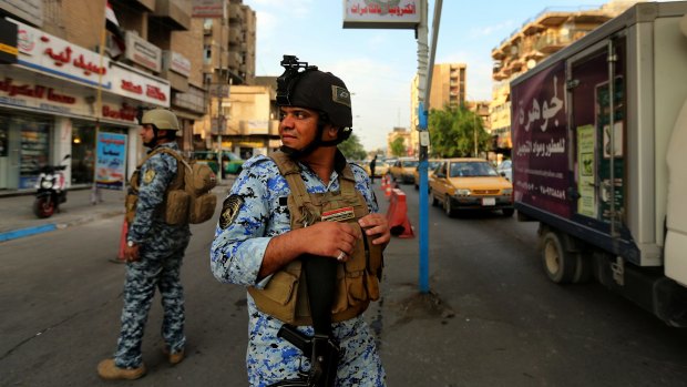 Nervous state: On a day when six bombs went off in the city, Iraqi policemen patrol Baghdad's Karrada district. 