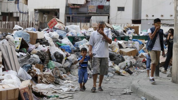 Residents cover their noses as they walk past rubbish piled up along a street in Beirut this week. 