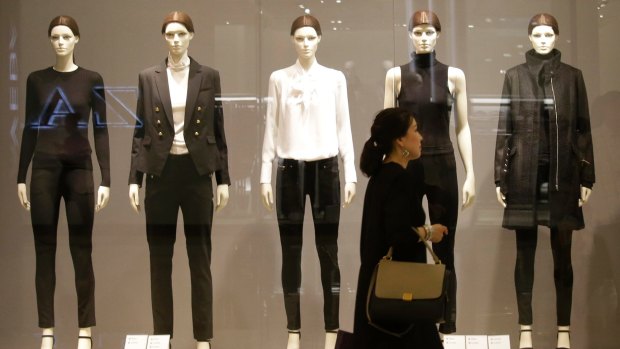 A woman walks in front of a display of mannequins wearing black and white clothing at a shopping mall in Bangkok, Thailand. Authorities are urging calm as social media throbs with criticism of people who aren't wearing black and white clothing to mourn the revered monarch and some arch-royalists take to reprimanding people in public.