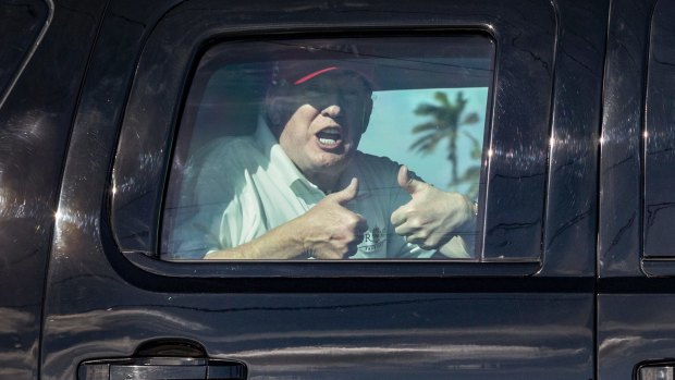 President Donald Trump gives two thumbs up to cheering supporters from his motorcade heading to his Mar-a-Lago estate after spending the morning at Trump International Golf Club on Friday.