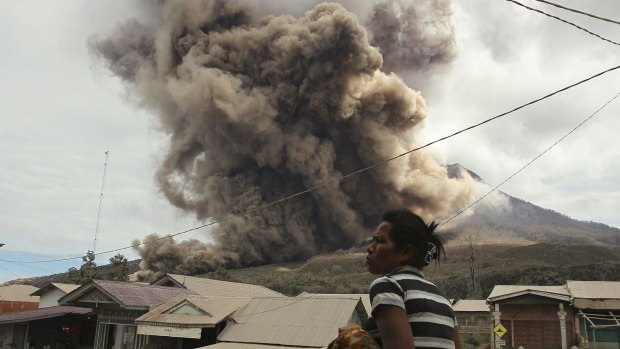 A resident looks on as Mount Sinabung erupts, as seen from Sukanalu village, North Sumatra.