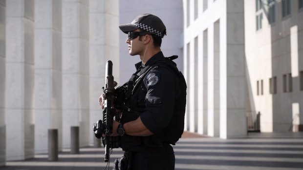 An armed AFP officer stands guard outside Parliament House in Canberra.