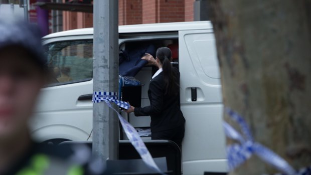 A person prepares to remove the bodies from the scene.