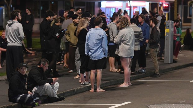 People evacuated from buildings stand in the street in the capital, Wellington.