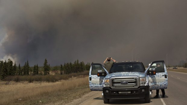 People stop to take photos of a wildfire south of Fort McMurray, Alberta, on Thursday.