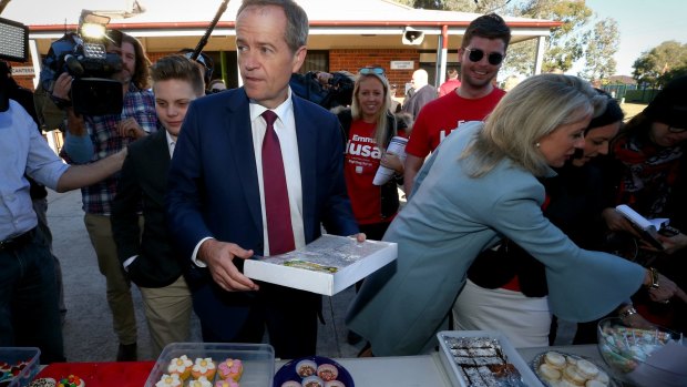 Opposition Leader Bill Shorten and wife Chloe purchase lamingtons for the media during a visit to a polling booth in Sydney.