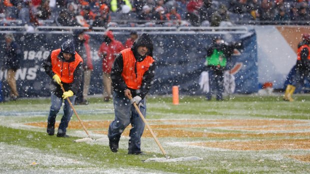 Members of the Soldier Field grounds crew clears snow in the end zone.