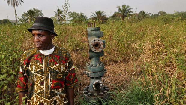 A Nigerian tribal chief stands alongside an abandoned oil wellhead, known as number 1 and previously operated by Royal Dutch Shell, in marshland in southern Nigeria.