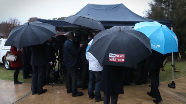 Prime Minister Tony Abbott and the media battle heavy rain for a press conference to spruik the government's Green Army initiative.