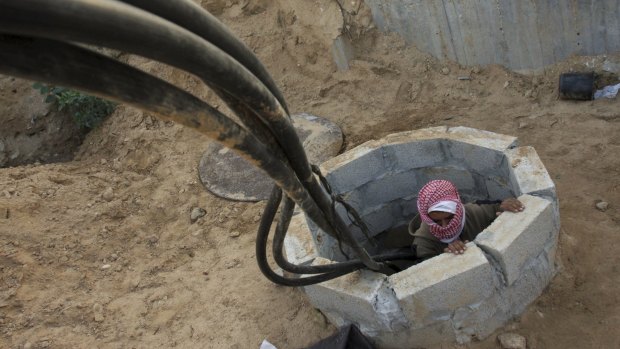 A Palestinian smuggler climbs from a tunnel alongside a hose used to bring fuel from Egypt to Gaza in 2008.