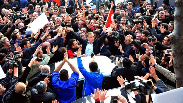 Show of supporter: Colleagues and supporters of <i>Zaman</i> newspaper surround editor-in-chief Ekrem Dumanli as he is arrested.