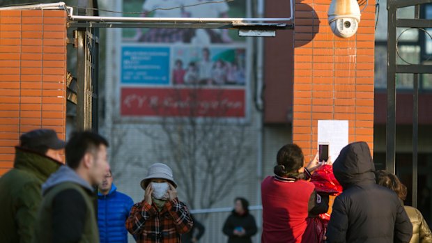 Parents take photos of a notice posted by the RYB kindergarten announcing measures taken in response to allegations of children abuse.