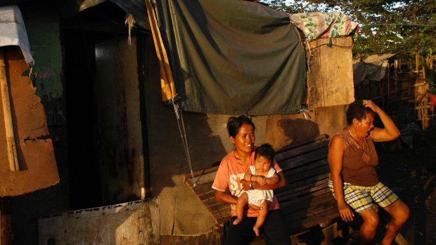 Rachel Abalos holds her  son Aaron, with Juanita Espinosa in front of her house in the slum 'Smokey Mountain' in Manila.