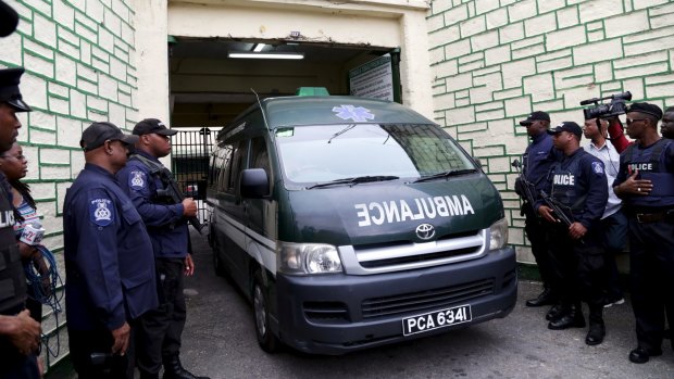 Police officers stand guard as an ambulance leaves the state prison in Port-of-Spain. Accused former FIFA vice president, Jack Warner, left jail in Trinidad and Tobago via ambulance, according to local media. 
