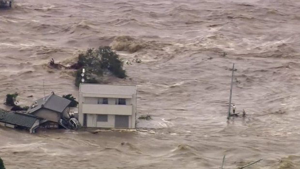 In this photo taken from video provided by Japan's TBS network, a man, right, stands stranded in the middle of raging floodwaters before being rescued by a military helicopter in Joso, Ibaraki prefecture.