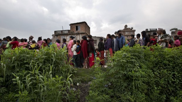 Villagers stand in a queue to receive food.