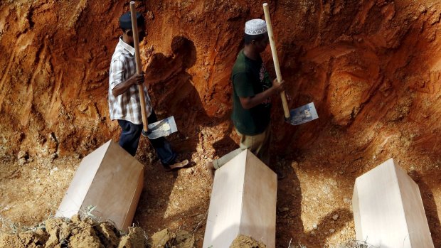Workmen among coffins in a mass grave of unidentified Rohingya remains found at a traffickers' camp in Wang Kelian, near Alor Setar, Malaysia, in June.