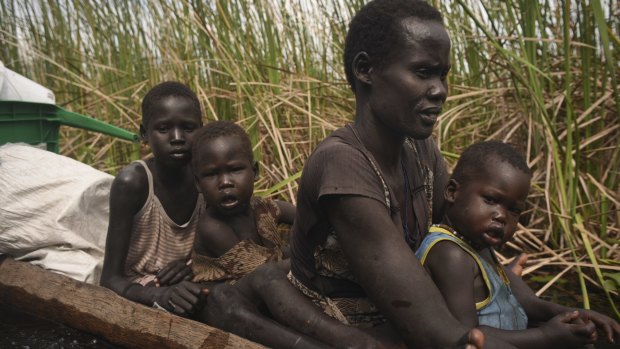 A displaced woman and her children ride in a wooden canoe through a swamp, where the thick reed marshes protect against attacks, as they flee from Kok Island to Nyal, South Sudan, earlier this month.