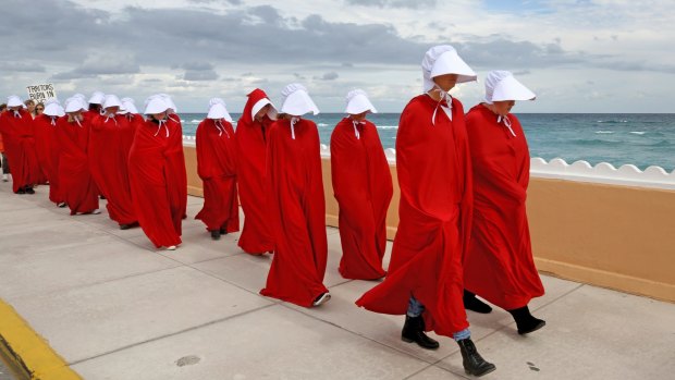 Protester dressed as handmaidens from <i> The Handmaid's Tale</i> march in protest of Donald Trump in West Palm Beach, Florida. 