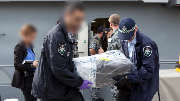 Australian Federal Police officers carry bags of cocaine.