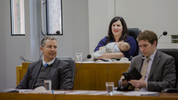 Giulia Jones breastfeeding her son Maximus in the ACT parliamentary chamber, with Liberal colleagues Jeremy Hanson and Alistair Coe in front.