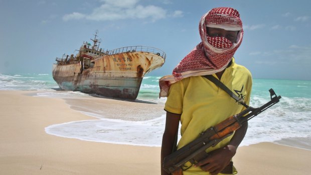 Masked Somali pirate Hassan stands near a Taiwanese fishing vessel in 2012, washed ashore after the pirates were paid a ransom and the crew were released in the once-bustling pirate den of Hobyo, Somalia. 