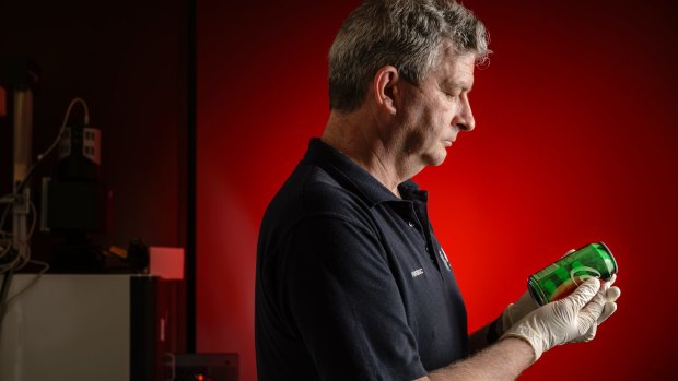Australian federal police fingerprints expert Phil Herd examines fingerprints on a can of soft drink.