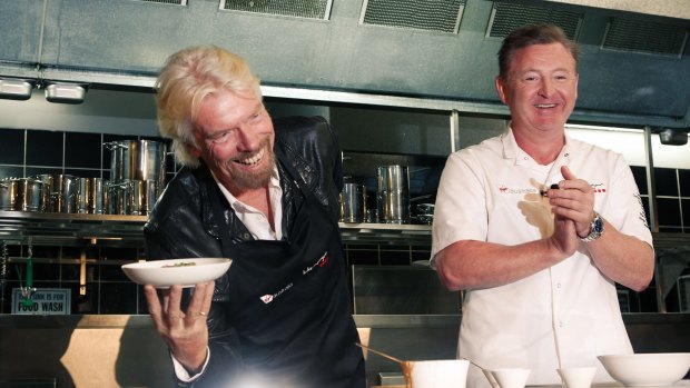 Sir Richard Branson shows off his new skill of plating a business class dish that he learnt from chef Luke Mangan.