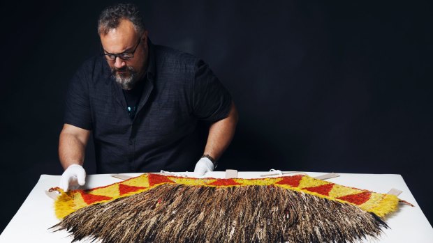 Logan Metcalfe, collections officer Pacific at the Australian Museum, examines the feathers of the rare cape given to Captain Cook by a Hawaiian chief.