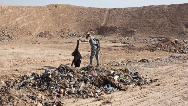An Iraqi Federal Police officer examines human remains at a site of a mass grave of victims of Islamic State militants in Hamam al-Alil, some 10 kilometers south of Mosul, Iraq.