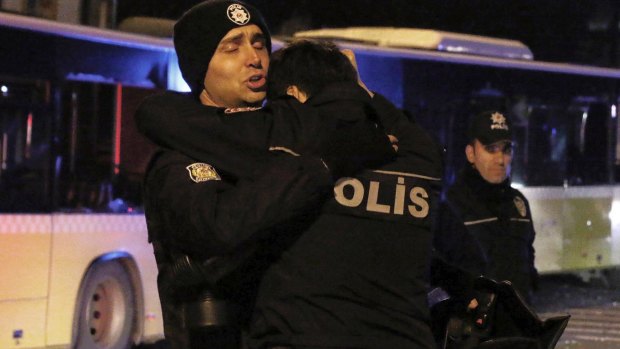 Police officers comfort each other after explosions near the Besiktas football club stadium.