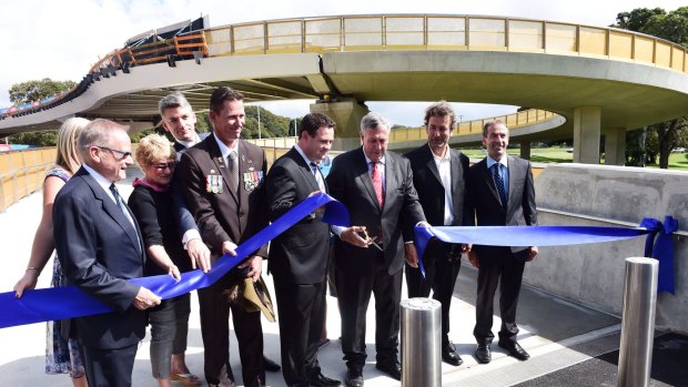 Dignitaries including Duncan Gay (with scissors) open the Albert "Tibby" Cotter walkway over ANZAC Parade earlier this year.