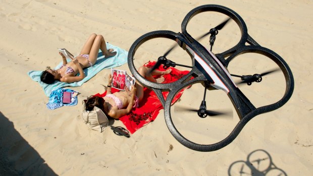 A remote controlled drone helicopter which can record video and photo's hovers above some sun bathers at Middle Park beach.